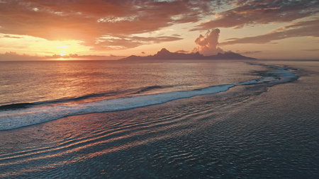 Aerial view of a spectacular sunset over Moorea island in French Polynesia, with warm colors...