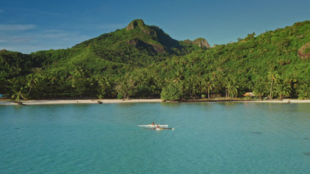 Aerial view of tourists rowing in the turquoise lagoon of Bora Bora, French Polynesia, with lush...