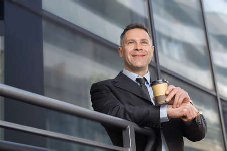 Young businessman having break time. He is drinking coffee outdoor.の写真素材