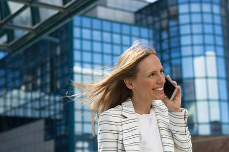 Smiling businesswoman talking on cell phone outdoorsの写真素材