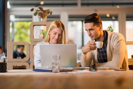 Smiling businesswoman with laptop enjoying in a cafe with her male coworker.の写真素材