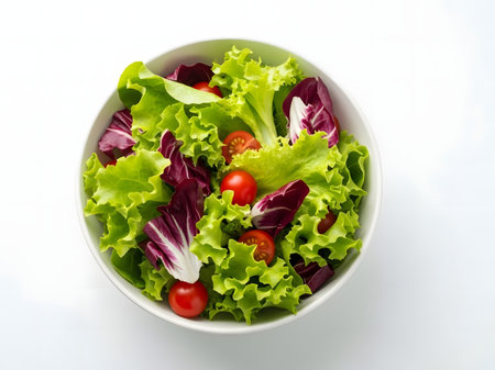 Green salad with cherry tomatoes in a bowl on a white background.の素材