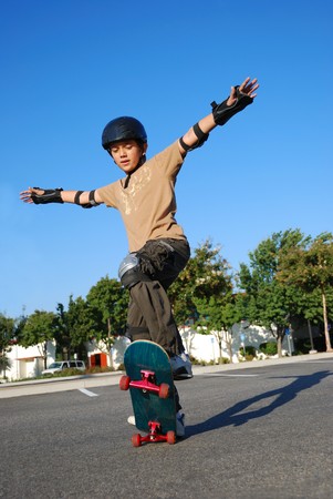 Boy doing stunts on a skateboard in afternoon sun with blue sky in the backgroundの写真素材