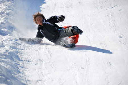 boy falling while sledding fast down the hilll with snow background