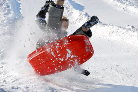 boy in the air while sledding fast down the hilll with snow background
