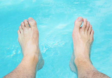 Two feet relaxing in the swimming pool water.の写真素材