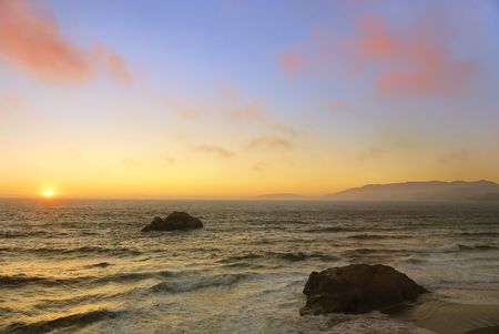 Sunset above the wavy Pacific as seen from the Ocean Beach in San Francisco, California.の写真素材