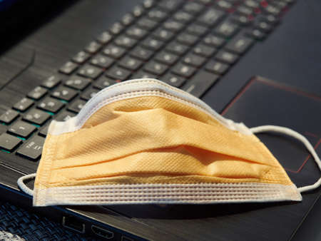 Yellow facial mask laying on keyboard work from homeの写真素材