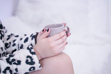 A girl in a bathrobe relax in the morning on the windowsill.