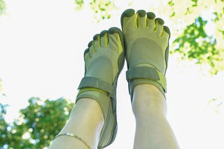 unusual sneakers with five fingers. strange shoes in summer in green Park on the grass.の写真素材