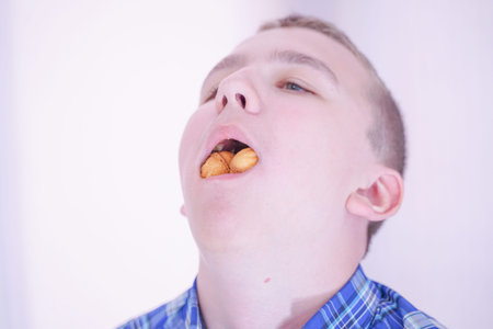 cute hungry teenager boy with fresh small bake sweets on white room background alone