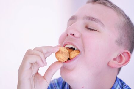 cute hungry teenager boy with fresh small bake sweets on white room background aloneの写真素材