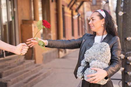 Happy mother taking red rose from sons hand