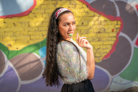 cute adult girl in colorful sweater with small cute lollipop standing outdoor