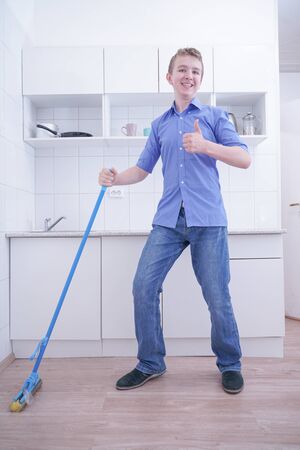Teenager Boy Mopping The Floor and helps his parents to clean on kitchenの写真素材