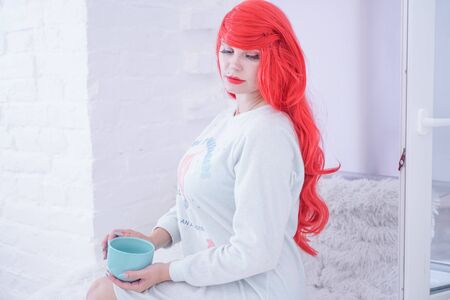 Tea time. Beautiful plus size woman holding ceramic cup of tea or coffee and enjoyの写真素材