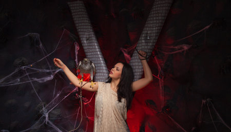 beauty brunette girl and a hawk on dark gothic scary studio background