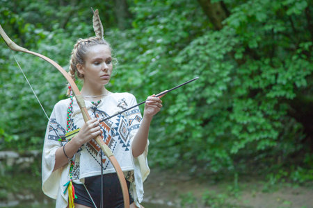 beautiful girl with american indian feathers holds bow and arrow