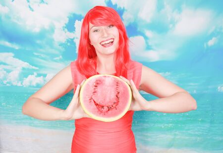 portrait of happy young bright woman holding slice half of watermelon over colorful blue backgroundの写真素材