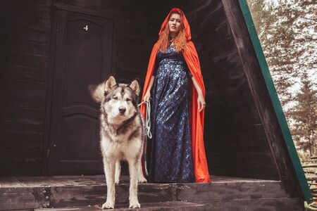 woman owner and her dog malamute near their triangular black house ready for walk in the forestの写真素材