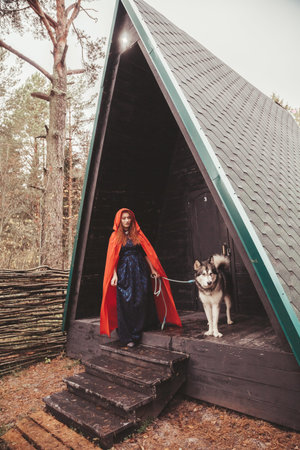 woman owner and her dog malamute near their triangular black house ready for walk in the forest