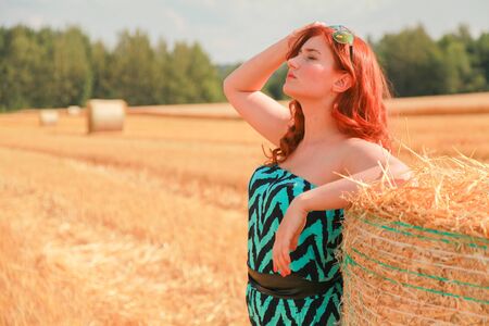 Woman in the autumn field landscape. Haystask rolls on agriculture field.の写真素材