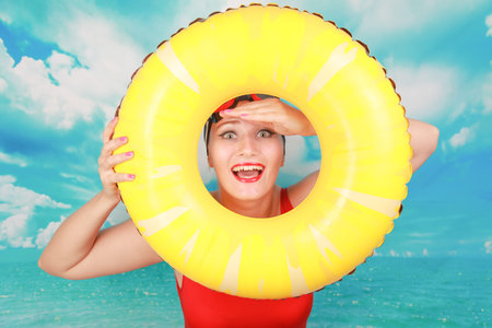 Studio shot of Beauty sexy women wear red vintage swimsuit and carrying life ring on blue sky...