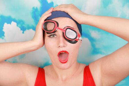 crazy diver in red swimsuit with swimming goggles on blue background. person swimmer learn to swim.の写真素材