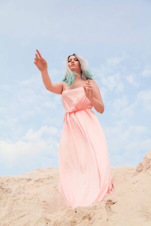 Young beautiful Caucasian girl stands on the mound of sand and looks downの写真素材