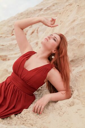 Young beautiful Caucasian woman lying alone in desert landscape with sand.の写真素材