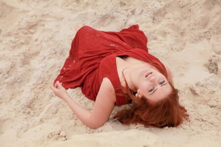 Young beautiful Caucasian woman lying alone in desert landscape with sand.の写真素材