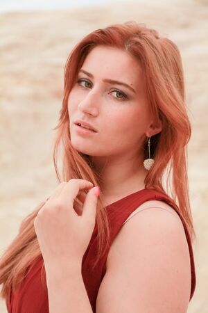 portrait of Young beautiful Caucasian redheaded woman posing in desert landscape with sand.の写真素材