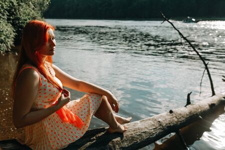 cute redheaded girl walking in the summer hot city parkの写真素材