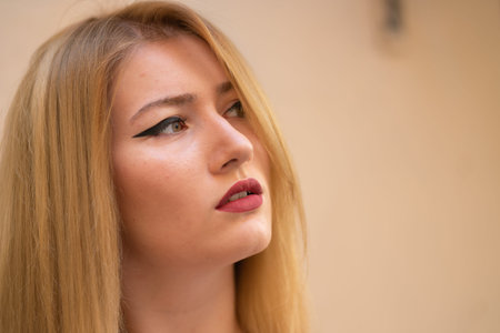 blonde girl with wide make up arrows on the eyes posing in the streetの写真素材