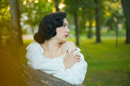 Close-up of a happy young pin up girl posing with tree at the parkの写真素材