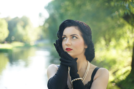 Portrait of beautiful pinup girl in black dress outdoor on the nature