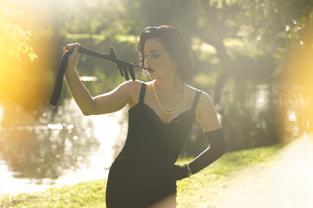 Beautiful young woman with pin-up make-up and hairstyle posing in the summer city park