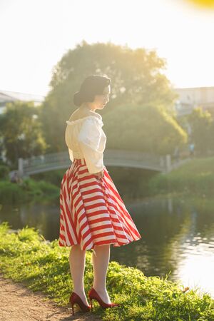 Vintage portrait of a woman in retro white and red dress in the city parkの写真素材