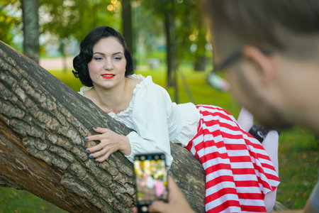 Woman is taken on pictures with her smartphone by her friend outdoor