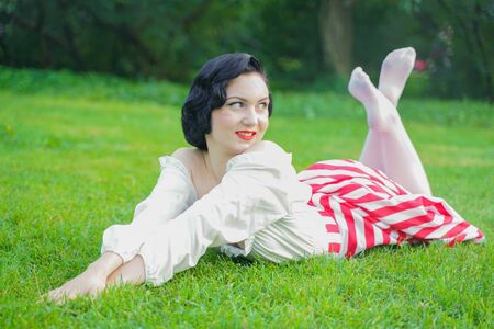 Vintage portrait of a woman in retro white and red dress in the city parkの写真素材