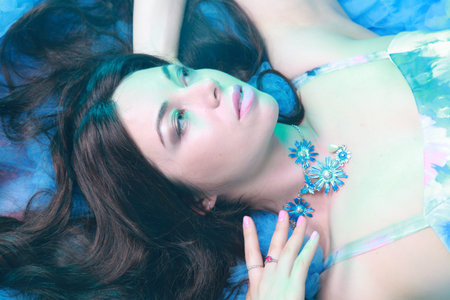 Young Woman Portrait in Evening Blue Long Dress on studio background