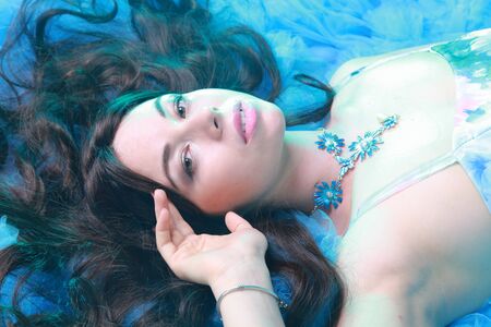 Young Woman Portrait in Evening Blue Long Dress on studio backgroundの写真素材