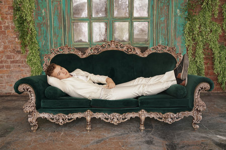 tired sleepy fashionable young man teenager stretches and yawns slightly in a white classic business...
