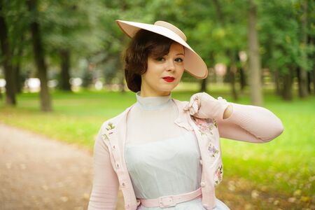 Portrait of pin up young woman in vintage dress and retro hat walkingの写真素材