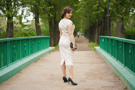 fashion portrait of young woman in classic pinup beige dress outdoor in the cityの写真素材