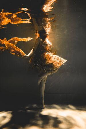 young woman swimming alone with fashion fabric underwater incognitoの写真素材