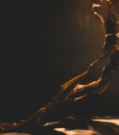 young woman swimming alone with fashion fabric underwater incognitoの写真素材