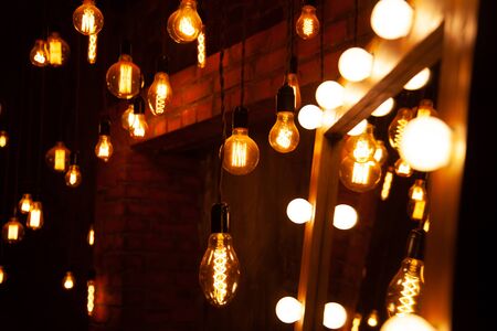 classic different retro light bulbs hanging on brick wall background at night.の写真素材