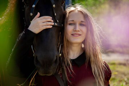 Beautiful caucasian young girl walking with a horse and enjoys summertime in countryside.の写真素材