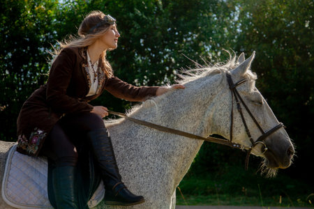 Beautiful caucasian young girl walking with a horse and enjoys summertime in countryside.の写真素材
